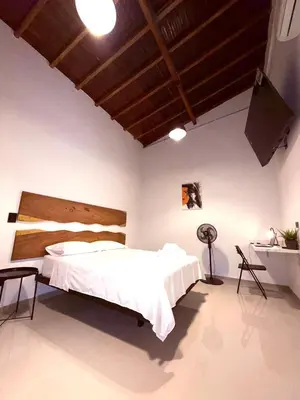 a bedroom with a white bed with a wooden headboard at Clandestino - Hotel Boutique in La Dorada