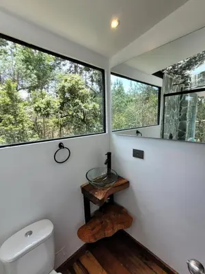 a bathroom with a toilet and two large windows at Cabaña Aventurina- La pascana Ecolodge Entorno natural excepcional, conexión con la naturaleza y avistamiento de aves, Ubicado a 3km del metrocable y Parque Arvi, Guarne in Mazo