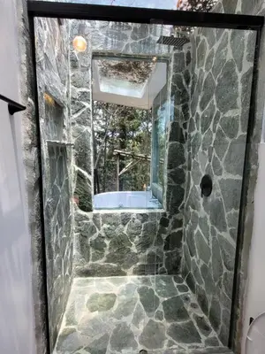 a bathroom with a stone shower with a mirror at Cabaña Aventurina- La pascana Ecolodge Entorno natural excepcional, conexión con la naturaleza y avistamiento de aves, Ubicado a 3km del metrocable y Parque Arvi, Guarne in Mazo