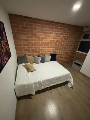 a bed in a room with a brick wall at Unidad recidencial San basilio in Sabaneta