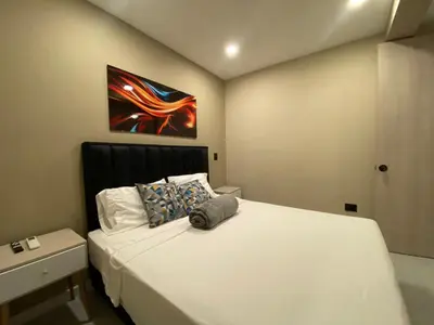 a bedroom with a white bed with a painting on the wall at Hermoso apartamento en el poblado in Medellín