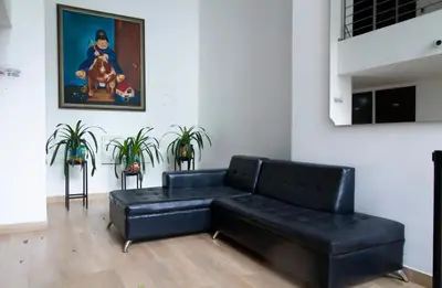 a black leather couch in a living room with a painting at Aparta loft in Envigado