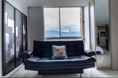 a blue couch in a room with a large window at Aparta loft in Envigado