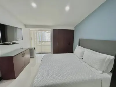a bedroom with a large white bed and a kitchen at Private Jacuzzi 3 Bedroom apartment in Provenza cartagena in Medellín