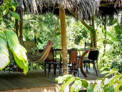a porch with chairs and a table and a hammock at El Refugio Eco Hostal Caracolí in Cascarón