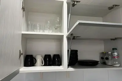 a white cabinet with wine glasses and other items at Moderno y cómodo cerca al cable in Manizales
