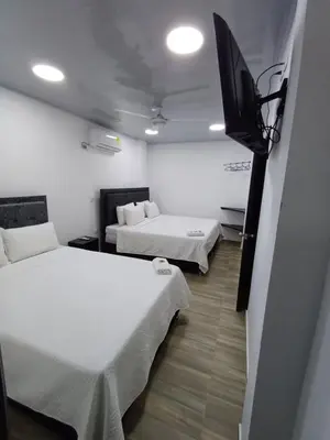 a room with two beds and a flat screen tv at Hotel Internacional Boutique Milan in Puerto Boyacá