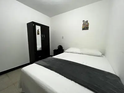 a white bedroom with a bed and a mirror at Hogar El Descanso Itagui in Itagüí