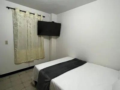 a bedroom with a bed and a television on the wall at Hogar El Descanso Itagui in Itagüí