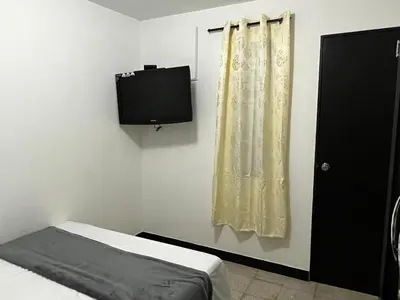 a bedroom with a bed and a tv on the wall at Hogar El Descanso Itagui in Itagüí