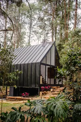 a black and white house in the woods at Cabaña Onix - La Pascana Ecolodge in Mazo