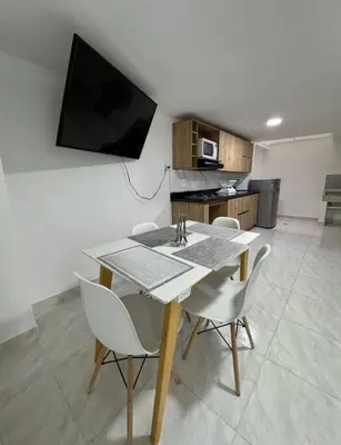 a dining room table with chairs and a television on a wall at Alojamiento en Sonsón in Sonsón