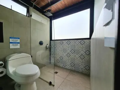 a bathroom with a toilet and a shower with a window at Los Bambúes in El Peñol