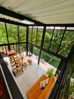 a living room with an orange couch and some windows at Los Bambúes in El Peñol