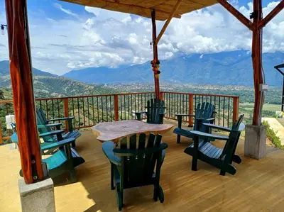 a porch with chairs and a table and a view of mountains at Vista preciosa-clima cálido-calma-pueblo histórico in Santa Fe de Antioquia
