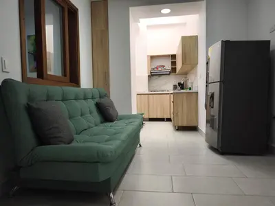 a living room with a green couch and a refrigerator at Apartamento nuevo en primer piso in Jardin
