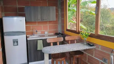 a kitchen with a refrigerator and a table with chairs at Cabaña Campestre San Gabriel in Angostura