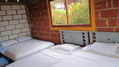 three beds in a room with a brick wall at Cabaña Campestre San Gabriel in Angostura