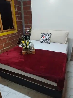 a large bed with a red blanket on it at Cabaña Campestre San Gabriel in Angostura