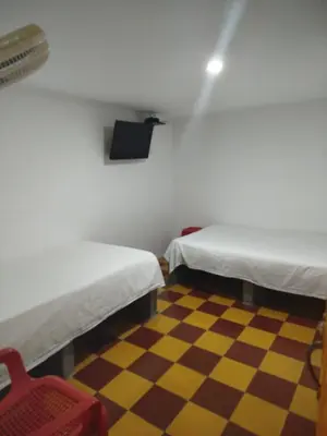 a room with two beds and a checkered floor at Habitación doble, con desayuno - La Casona Hotel in La Pintada