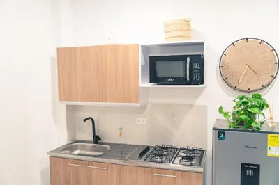 a kitchen with a microwave and a stove and a clock at Apto 203 - Casa bendita in Medellín