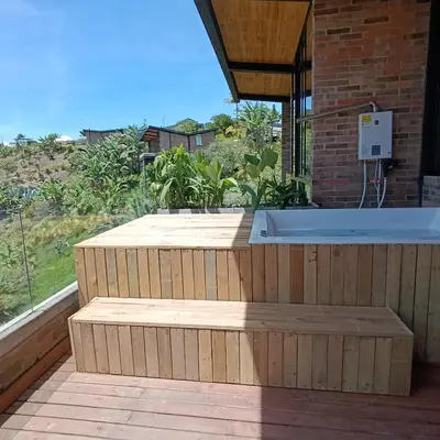 a hot tub on a wooden deck with a view of a field at Babakan in San Rafael