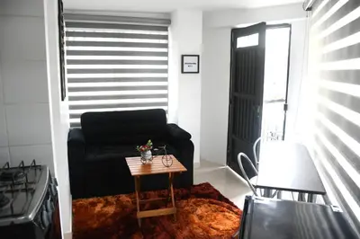 a living room with a black couch and a table at Divino Apartamento Moderno con la Mejor Ubicación in Manizales