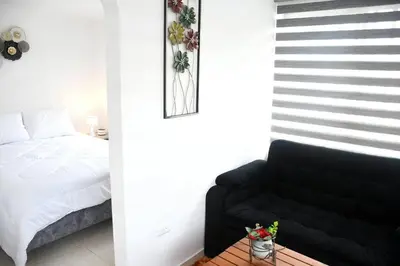 a bedroom with a bed and a black couch at Divino Apartamento Moderno con la Mejor Ubicación in Manizales