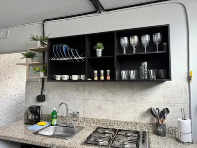 a kitchen counter with a sink and glasses on shelves at Spacious dream house Medellín Laureles in Medellín