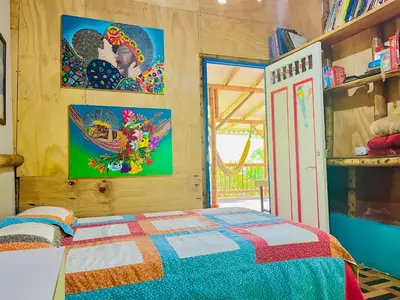a bedroom with a bed and two paintings on the wall at Hospedate entre Cascadas, Senderos y Paisajes Naturales in Jardin