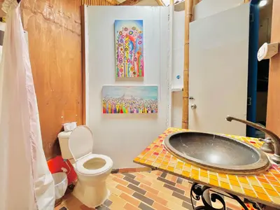 a bathroom with a sink and a toilet and paintings at Hospedate entre Cascadas, Senderos y Paisajes Naturales in Jardin