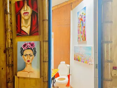 a bathroom with a toilet and paintings on the wall at Hospedate entre Cascadas, Senderos y Paisajes Naturales in Jardin