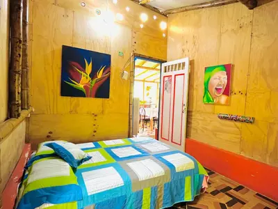 a bedroom with a bed and paintings on the walls at Hospedate entre Cascadas, Senderos y Paisajes Naturales in Jardin