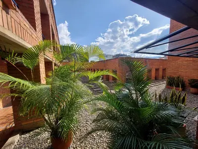 a courtyard with palm trees in front of a brick building at Loft en el exclusivo barrio Poblado - Medellín in Medellín