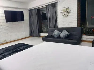 a bedroom with a bed and a couch and a tv at Loft en el exclusivo barrio Poblado - Medellín in Medellín