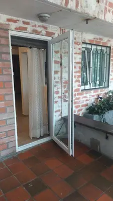 an open sliding glass door with windows on a brick wall at International House Co-Living in Medellín
