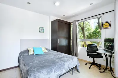 a bedroom with a bed and a desk with a computer at International House Co-Living in Medellín