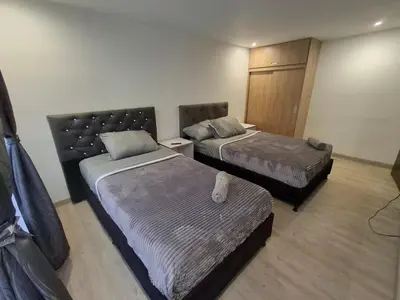 a hotel room with two beds and a bench in it at Hermosa casa con espacios independientes cerca a Mall plaza in Manizales