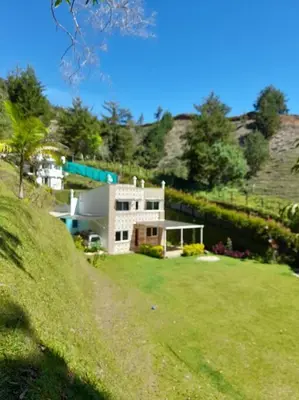 a house on a hill with a grassy yard at Acogedora Casa De Campo Con Jakuzzi, Descanso Garantizado in El Peñol