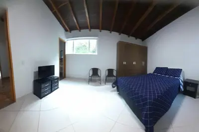 a bedroom with a blue bed and a television at Acogedora Casa De Campo Con Jakuzzi, Descanso Garantizado in El Peñol