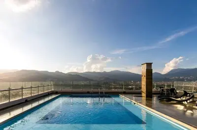 a swimming pool on top of a building with mountains in the background at Amazing apartment in el Poblado in Medellín