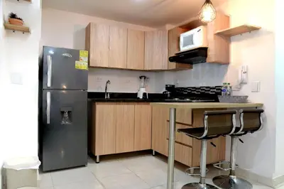 a kitchen with a stainless steel refrigerator and wooden cabinets at ALOJARTE RIONEGRO - Acogedor estudio - ubicación privilegiada in Rionegro