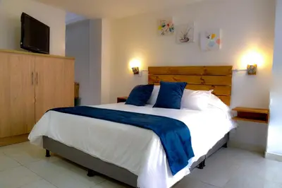 a bedroom with a large bed with a blue blanket at ALOJARTE RIONEGRO - Acogedor estudio - ubicación privilegiada in Rionegro