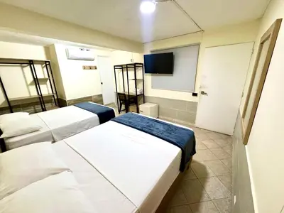 a hotel room with two beds and a tv at Hotel Estadio 80 in Medellín
