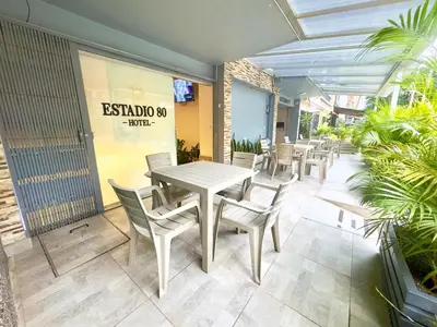 a patio with a table and chairs in a restaurant at Hotel Estadio 80 in Medellín