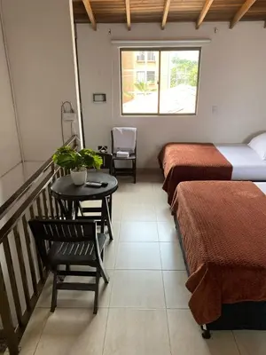 a room with two beds and a table and a balcony at Hermoso Aparta-Estudio En Envigado cerca de Medellin in Envigado