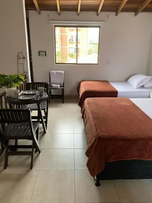 a hotel room with two beds and a table and a chair at Hermoso Aparta-Estudio En Envigado cerca de Medellin in Envigado