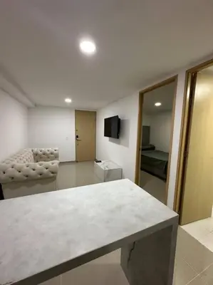 a living room with a table and a room with a couch at Medellín central in Medellín