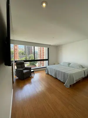 a bedroom with a bed and a chair and a window at Apartamento Montreal in Medellín