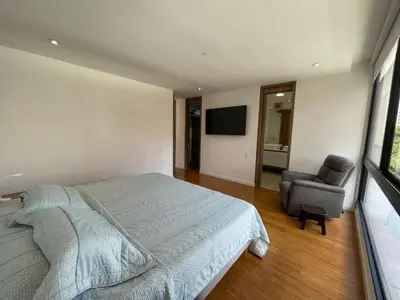a bedroom with a bed and a chair and a television at Apartamento Montreal in Medellín